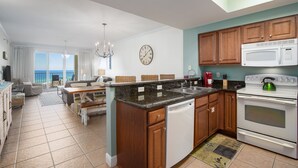 A modern kitchen with wooden cabinets, a built-in microwave, and a dishwasher. - Coastal Soul Beach Seascape Resort Pools (Miramar Beach)
