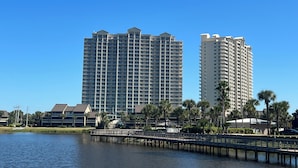 A high-rise hotel with multiple floors, a waterfront view, and a dock extending into the water. - Coastal Soul Beach Seascape Resort Pools (Miramar Beach)