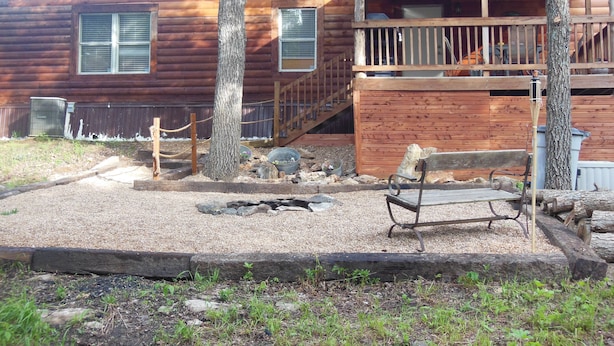 A wooden cabin with a porch, a bench, and a small garden area with gravel and rocks. -  CABIN IN THE WOODS , FAMILY AND PET FRIENDLY (Warsaw)