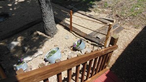 A wooden deck with a metal railing, surrounded by gravel and a tree. -  CABIN IN THE WOODS , FAMILY AND PET FRIENDLY (Warsaw)