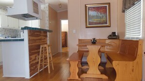 A kitchen with wooden countertops, a bar stool, and a dining table with benches. -  CABIN IN THE WOODS , FAMILY AND PET FRIENDLY (Warsaw)