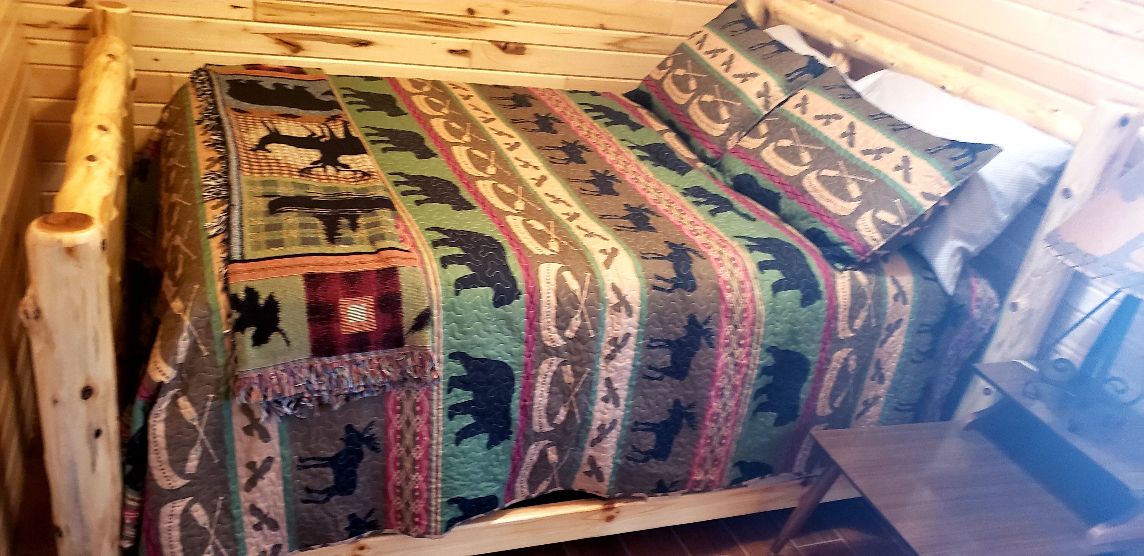 Una cama de madera con un colcha colorida adornada con motivos de animales.