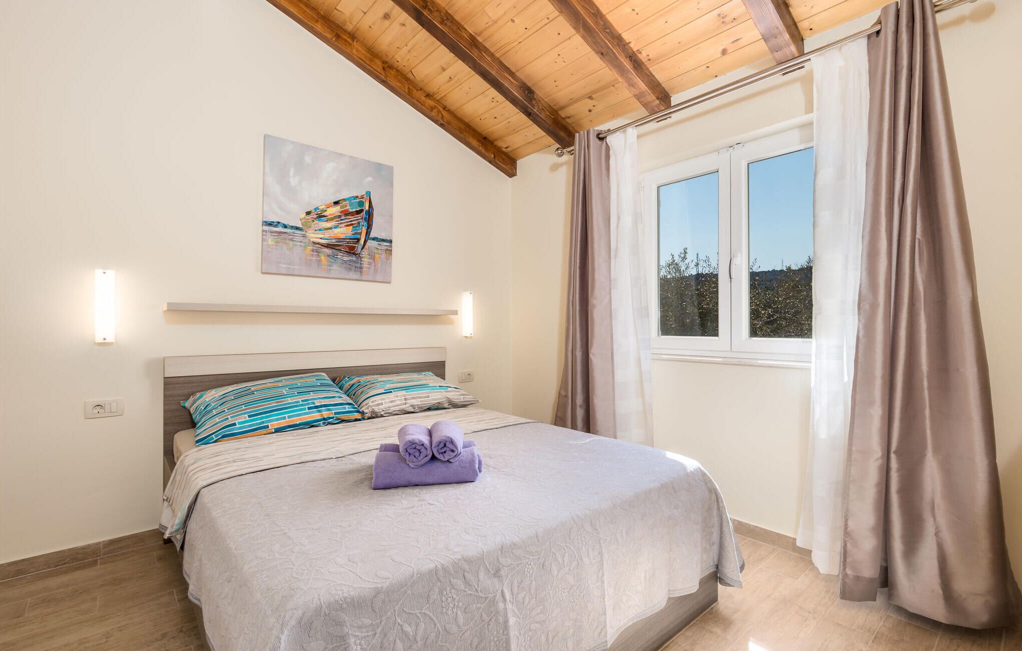 Une chambre à coucher avec un lit, un tableau, une fenêtre avec des rideaux et un plafond en bois.
