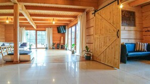 A spacious room with a large wooden door, a sofa, and several potted plants. - 4 bedroom stunning home in Ustka (Ustka)