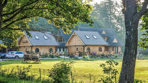 A rustic wooden cabin with a sloped roof, surrounded by a well-maintained lawn and a fence. - 4 bedroom stunning home in Ustka (Ustka)
