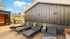 Une terrasse avec des chaises longues noires, une petite table et des plantes en pot.