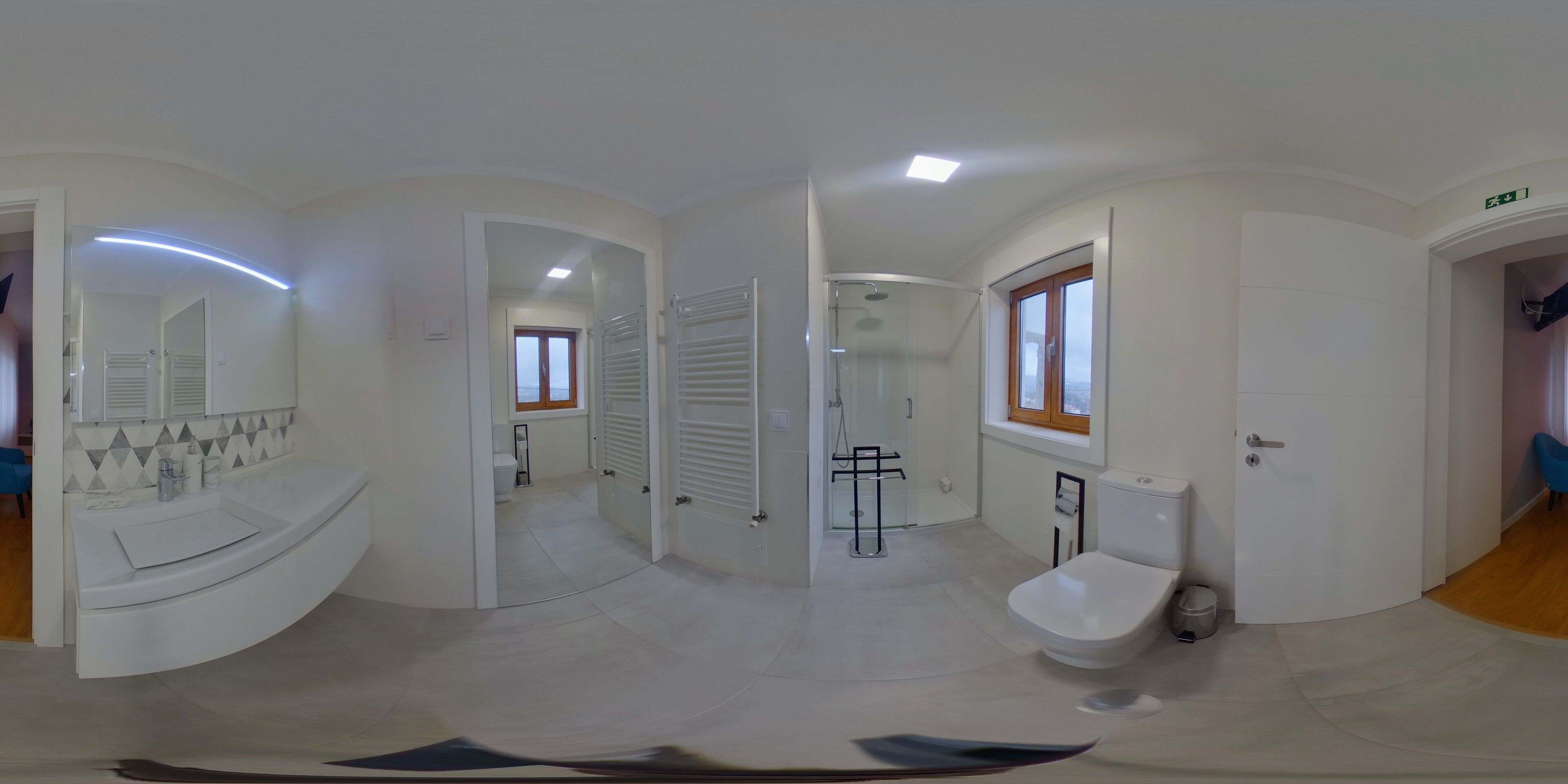 Casa de banho moderna com sanita, bidé e chuveiro. Há um espelho e uma janela.