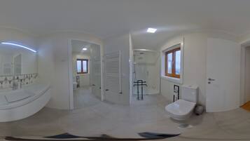 Casa de banho moderna com sanita, bidé e chuveiro. Há um espelho e uma janela.
