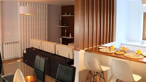 A modern dining area with a glass table, black and white chairs, and a wooden partition. - Villa Tavares Guest Houses (Arouca)