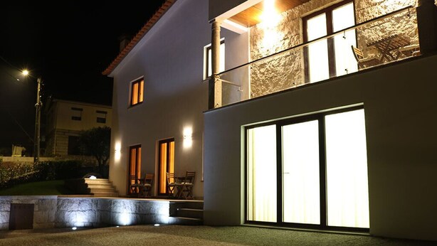 A modern two-story building with a balcony, large windows, and outdoor seating. - Villa Tavares Guest Houses (Arouca)
