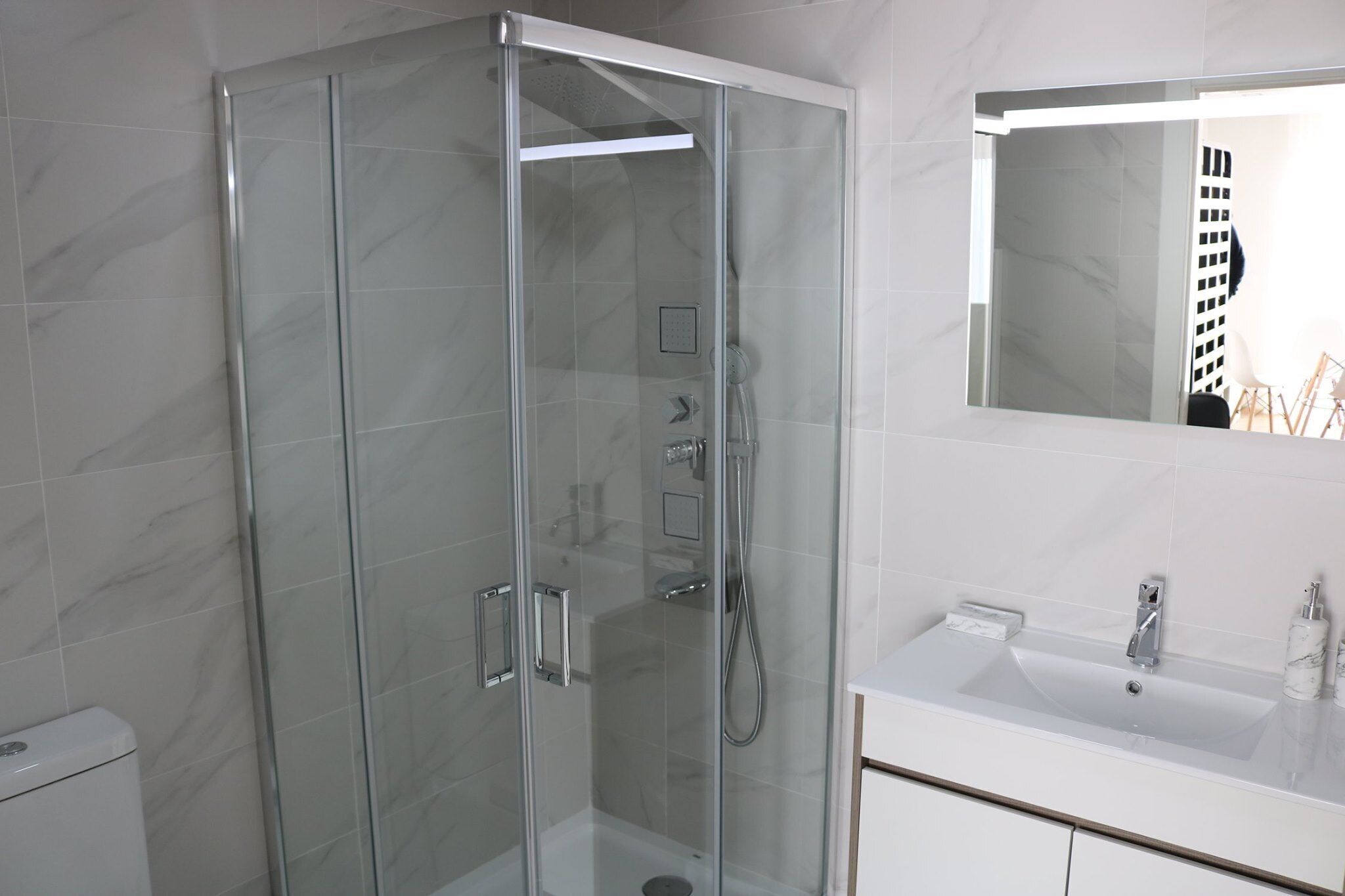 A modern bathroom with a glass-enclosed shower, a white sink, and a mirror above the sink.