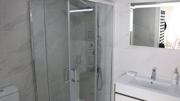 A modern bathroom with a glass-enclosed shower, a white sink, and a mirror above the sink.
