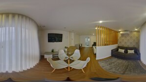A modern living room with a glass-top coffee table, white chairs, a sofa, and a patterned rug. - Villa Tavares Guest Houses (Arouca)
