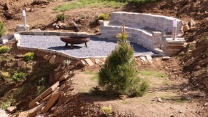 A landscaped area with a stone structure, a metal bowl, and a small tree. - Alpine chalet Klippitzzauber (Bad St. Leonhard im Lavanttal)