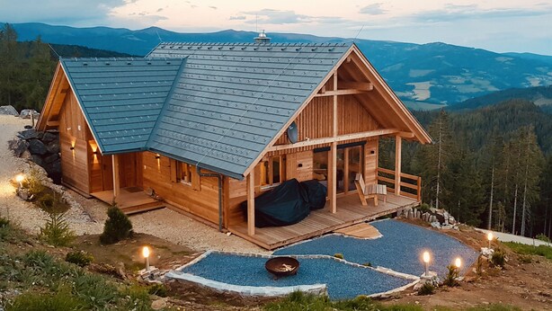 A wooden cabin with a sloped roof, a porch, and a fire pit area. - Alpine chalet Klippitzzauber (Bad St. Leonhard im Lavanttal)