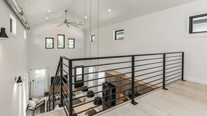 Amplio espacio tipo loft con techo alto, una escalera moderna y un gran ventanal que proporciona luz natural.