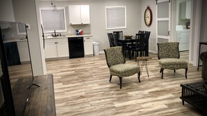 A modern kitchen with white cabinets, a dishwasher, and a dining area with two leopard print chairs.