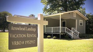 A vacation rental sign for Arrowhead Landings with a house in the background.