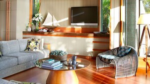 Una sala de estar moderna con techo de madera, televisor de pantalla plana, sofá, mesa de centro y una silla.