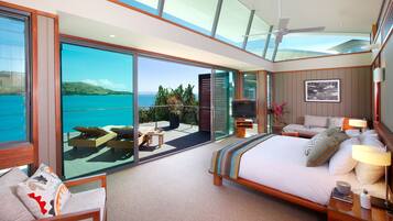 Habitació d'hotel moderna amb un llit gran, una televisió i un balcó amb vista al mar.