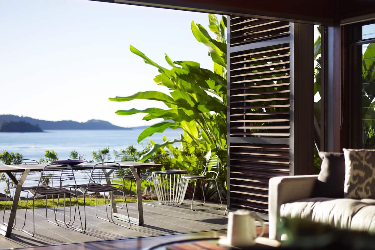 A terrace with a table and chairs, a sofa, and a view of the sea.