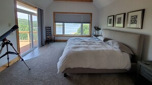 A bedroom with a large bed, a ceiling fan, a window with a view, and a telescope on a tripod. - Camp Roberts-Lakefront-8 Bedrooms-Sleeps 19-Big; Lake View-Community Pool! (Garfield)