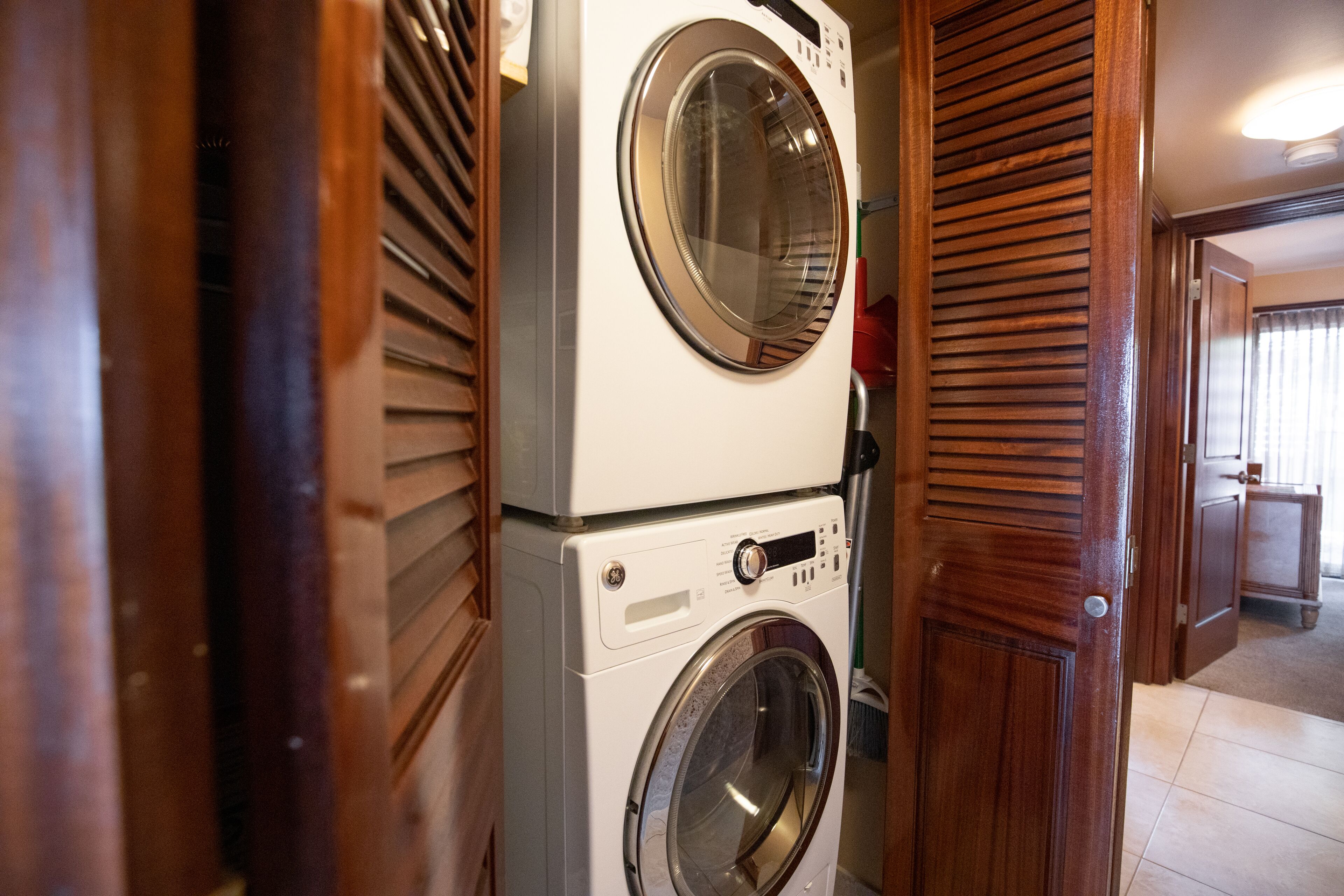 A laundry area with stacked washing machines and a wooden door.