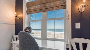 Une pièce avec une grande fenêtre, une table blanche et deux chaises.