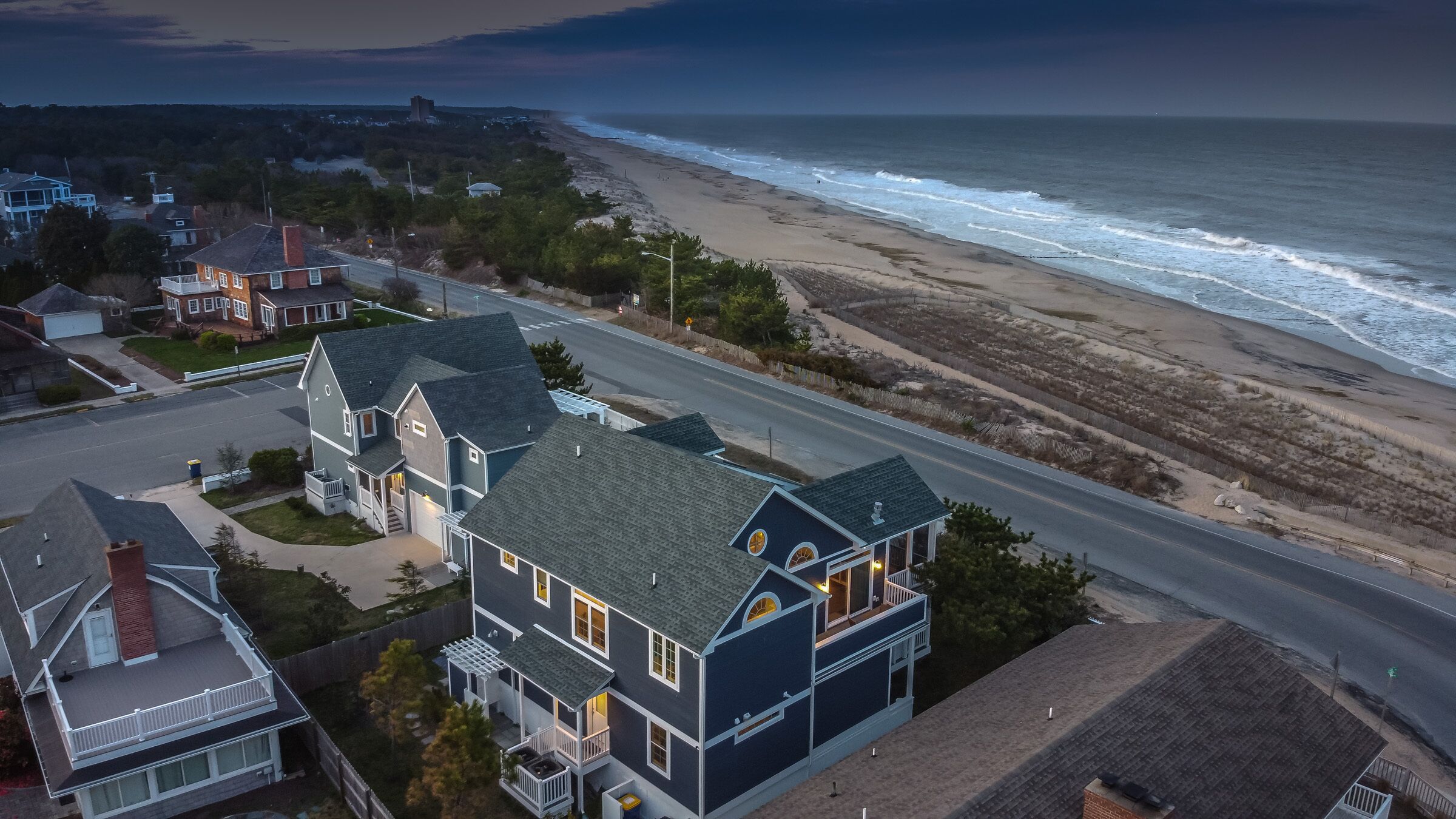 A coastal residential area with houses along a beachfront road.