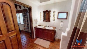 Une salle de bain avec un plancher en bois, un meuble-lavabo à deux vasques, un miroir et un porte-serviettes.