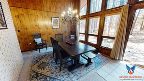 A dining area with a wooden table, chairs, and a chandelier. - Close to Country Club | Fireplace | Single Level | Happy Pines (Angel Fire)