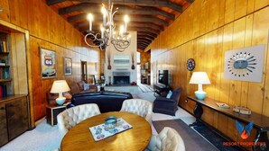 A cozy room with a fireplace, a dining table, and a TV. - Close to Country Club | Fireplace | Single Level | Happy Pines (Angel Fire)