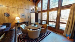 A cozy room with a wooden interior, a round table with chairs, a lamp, and a clock on the wall. - Close to Country Club | Fireplace | Single Level | Happy Pines (Angel Fire)