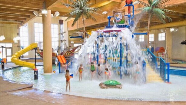 An indoor water park with a central water feature, slides, and a pool area. - Relax and make fun memories in our Vacation Home at Bridges Bay Resort (Arnolds Park)