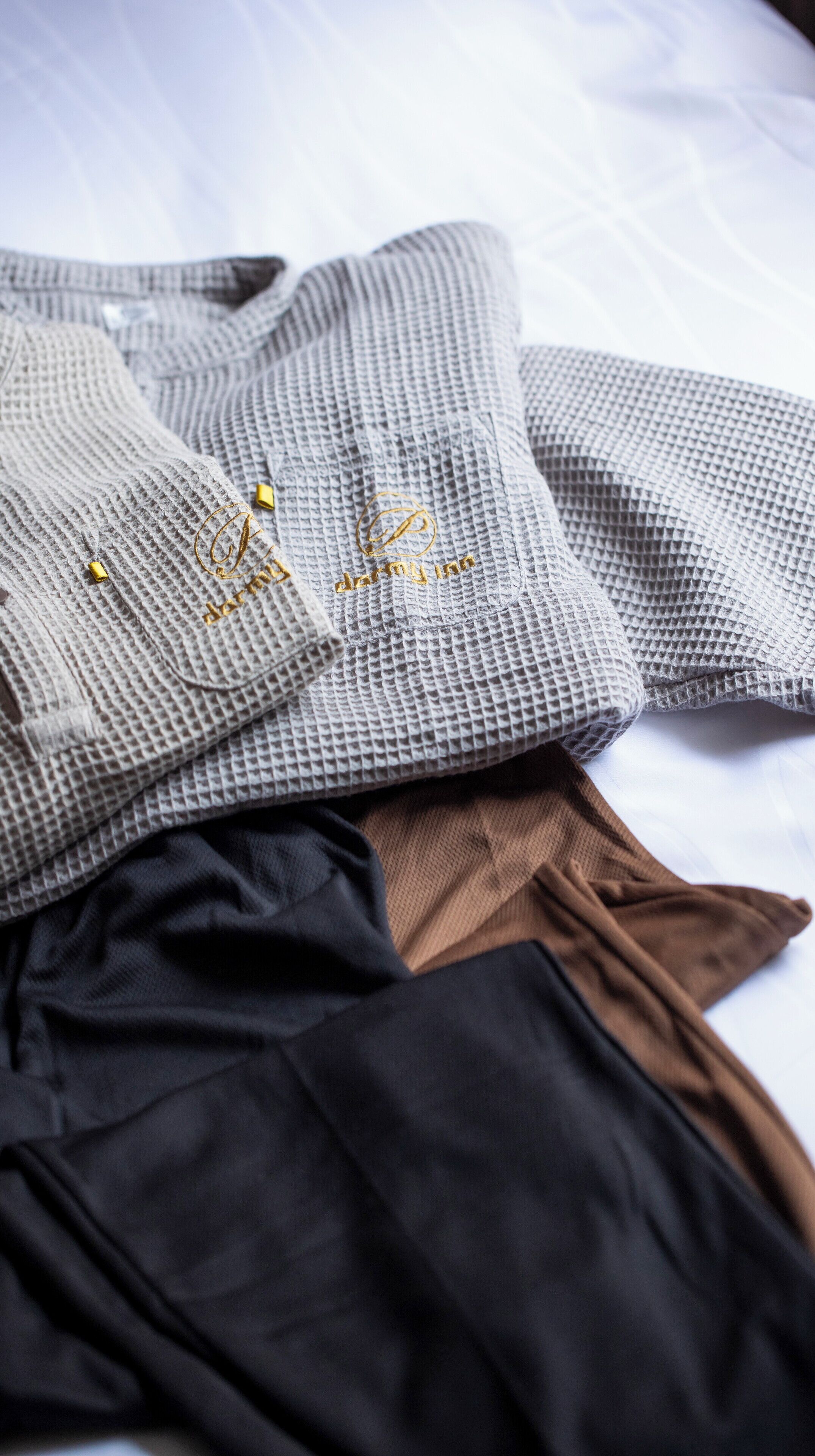 A neatly folded gray sweater with a gold embroidered logo and a brown skirt.