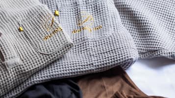 A neatly folded gray sweater with a gold embroidered logo and a brown skirt.