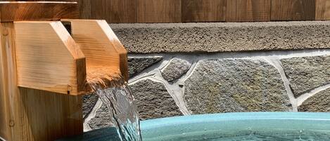 Ein hölzernes Wasserelement mit fließendem Wasser in einem Becken.