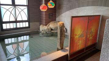 A spa area with a stone bath, a tiled floor, and a large window with a geometric design.