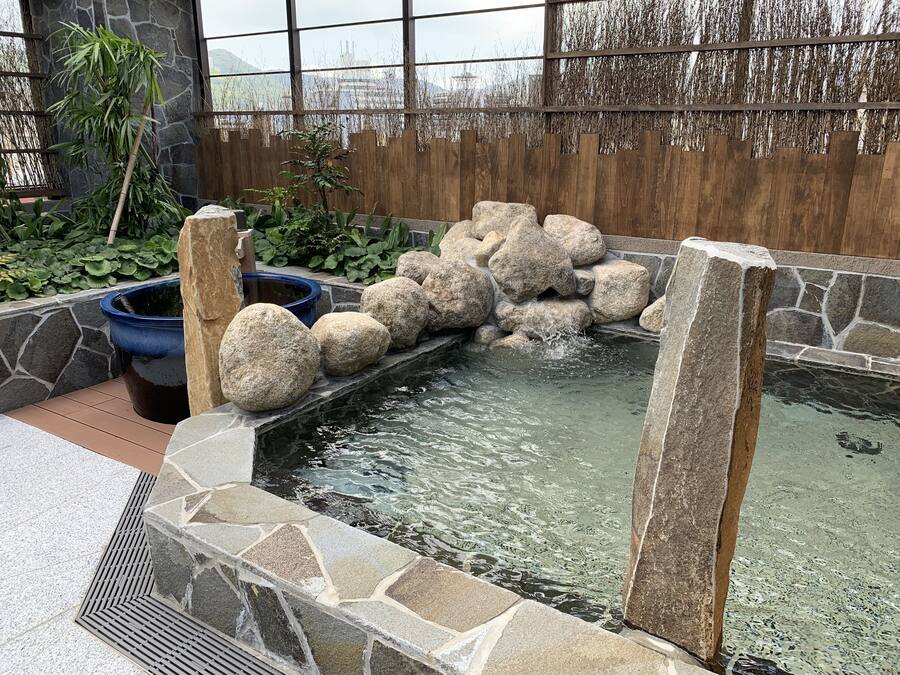 A koi pond with a stone border and a wooden fence in the background.