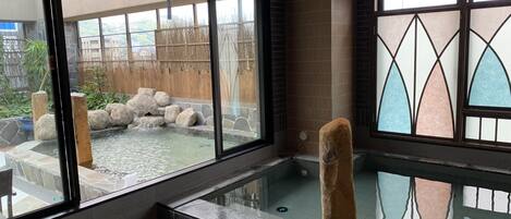 A spa area with a hot tub, stone walls, and a view of a garden.