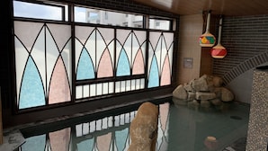 A room with a large window featuring stained glass, a stone wall, and a small indoor water feature. - Dormy Inn Nagasakiekimae Hot Springs (Nagasaki)