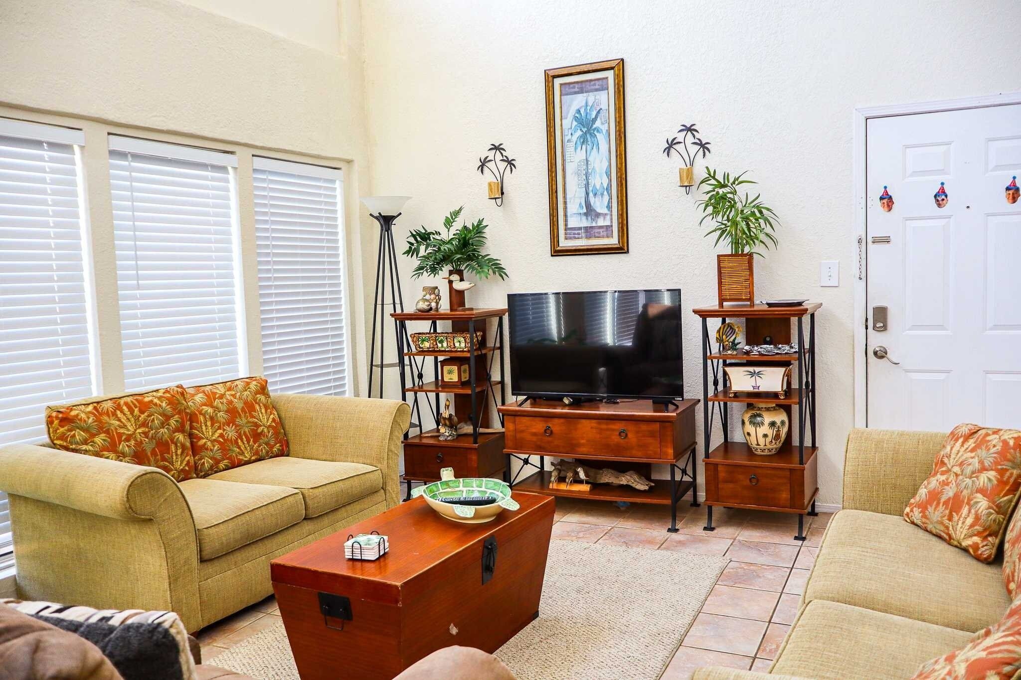 A living room with a sofa, a coffee table, a TV, and decorative items.