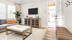 A modern living room with a sofa, a coffee table, a cabinet, and a TV mounted on the wall. - Family Fun Getaway #2333 5 Bedroom Townhouse by RedAwning (Washington)