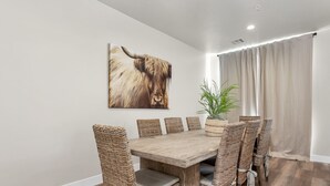 A dining area with a wooden table and wicker chairs, a large animal print artwork on the wall, and a potted plant. - Family Fun Getaway #2333 5 Bedroom Townhouse by RedAwning (Washington)