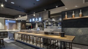 A modern kitchen with a long counter, stools, and a visible ventilation system. - APA Hotel Nagoya Ekimae Kita (Nagoya)