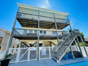 A multi-story building with a pool area, including a staircase and a fenced deck.