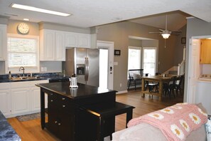 A modern kitchen with a central island, stainless steel appliances, and a dining area with a wooden table and chairs.