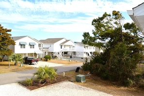 A row of white single-story houses with attached porches, a gravel driveway, and a small parking area. - Carmels By The Sea 4 Bedroom Home by RedAwning (Supply)