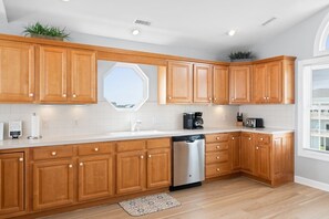 Eine moderne Küche mit Holzausstattung, Geschirrspüler, Kaffeemaschine und Blick auf die Stadt durch ein großes Fenster.