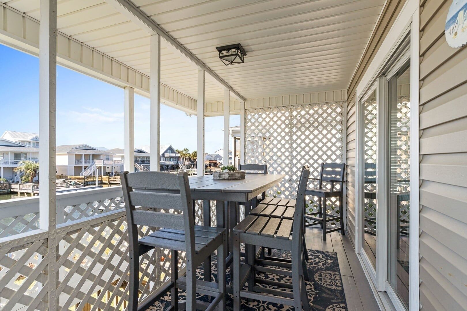 A covered outdoor area with a table and chairs, a railing, and a view of other buildings.